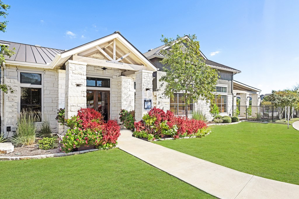 a home with a green lawn and flowers in front of it